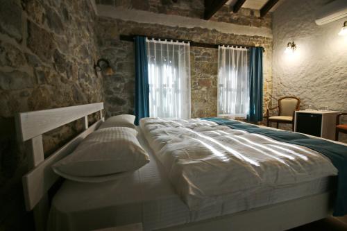 a large bed in a bedroom with a stone wall at Homeros Butik Otel in Dikili