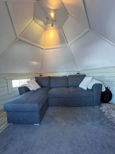 a couch in a living room with a ceiling at Camp Caroli Hobbit Hut in Jukkasjärvi