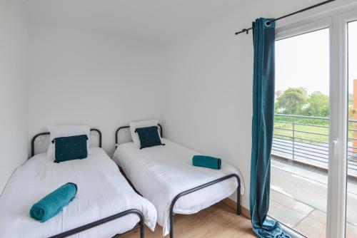 two beds in a room with a window at Le Guillaume - Sauna - A moins de 2 km de la plage in Sainte-Honorine-des-Pertes