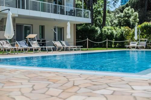 a swimming pool with chairs and umbrellas next to a house at Le Dune Verdi in Lido di Jesolo