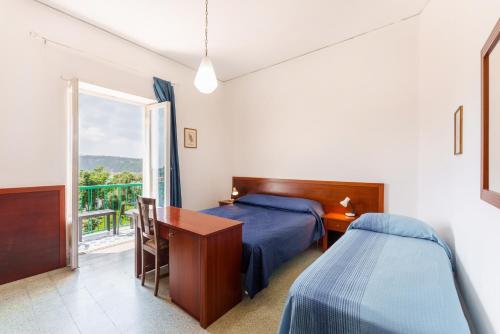 Schlafzimmer mit einem Bett, einem Schreibtisch und einem Fenster in der Unterkunft Hotel Riviera in Procida