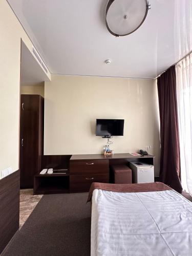 a bedroom with a bed and a desk with a television at Hotel Atmosphere in Poltava