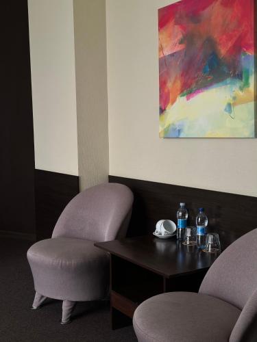 a room with two chairs and a table and a painting at Hotel Atmosphere in Poltava