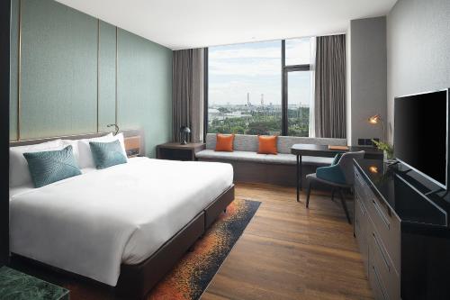una camera d'albergo con letto, divano e TV di Hotel Nikko Amata City Chonburi a Chon Buri