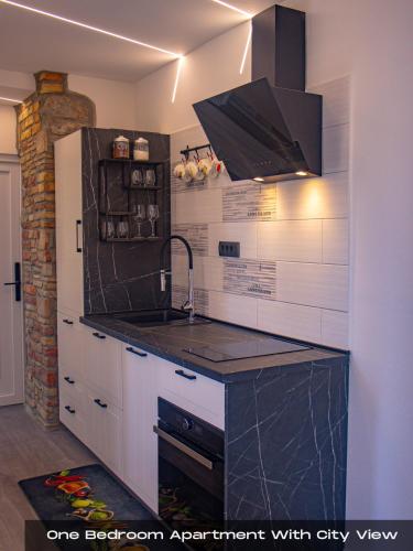 a kitchen with white cabinets and a black counter top at Villa Volos , free private parking in Opatija