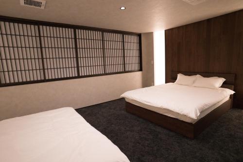 a bedroom with two beds and a window at Musashi Condo Kanazawa in Kanazawa