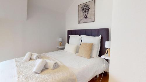 a bedroom with a large bed with white sheets and pillows at Triplex Le Bel Âtre in Sélestat