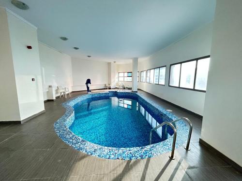 a swimming pool in a building with a person in the background at Al Hayat Suites Apartment in Manama