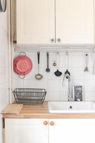 La cuisine est équipée de placards blancs, d'un évier et d'ustensiles. dans l'établissement TY GWENN - Jolie Maison avec sauna proche mer, à Ploudalmézeau