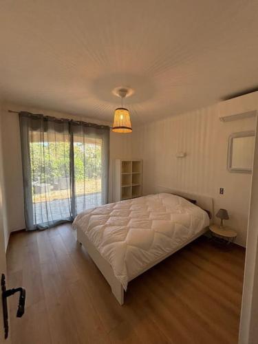 une chambre avec un grand lit et une grande fenêtre dans l'établissement St Aygulf, appartement climatisé 70m2, piscine privée , 4 personnes, à Saint-Aygulf