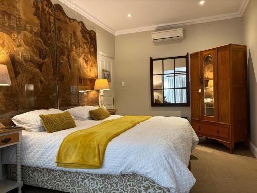 a bedroom with a large bed and a large painting on the wall at La Pension Guest House in Oudtshoorn