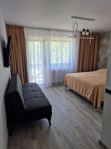 Un dormitorio con una cama y un sofá y una ventana. en Vila Roua Urseiu, en Urseiu