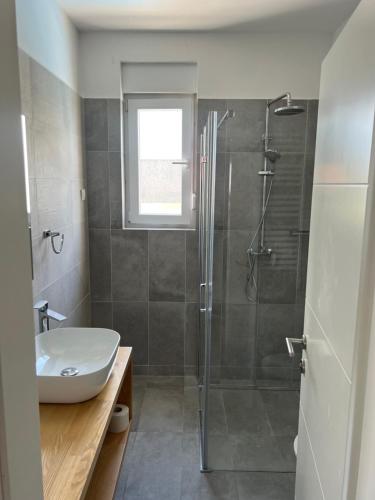 La salle de bains est pourvue d'une douche et d'un lavabo. dans l'établissement The Palms Luxury Pool Aparthotel, à Novalja