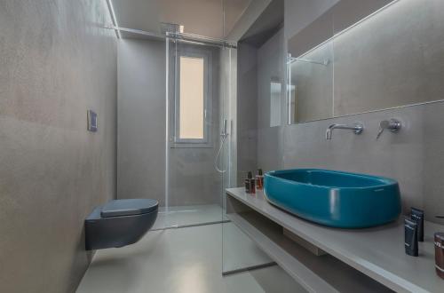 Fiveplace Design Suites & Apartments في تراباني: حمام مع حوض أزرق ومرحاض