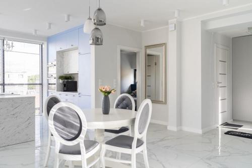 a white dining room with a white table and chairs at Mi Bella 1 in Gdynia