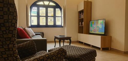 a living room with a couch and a tv at Dar Tan-Nanniet - House of Character with Private Pool in Żejtun
