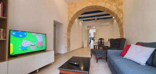 a living room with a couch and a flat screen tv at Dar Tan-Nanniet - House of Character with Private Pool in Żejtun