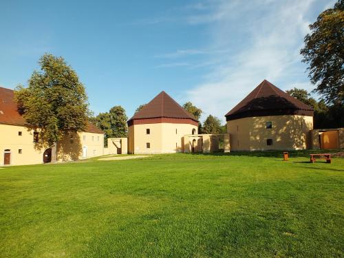 two buildings in a field with a green field at Zámecký Dvůr Černousy in V Poli
