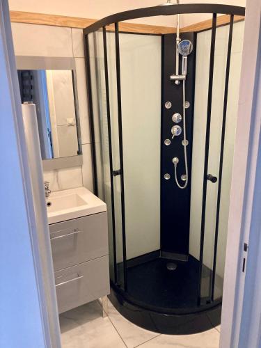 une salle de bain avec une douche avec un lavabo et un miroir dans l'établissement Maison de ville idéalement située, au Bourg-dʼOisans