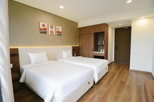 two beds in a hotel room with white sheets at Glamour Boutique Hotel in Phan Rang