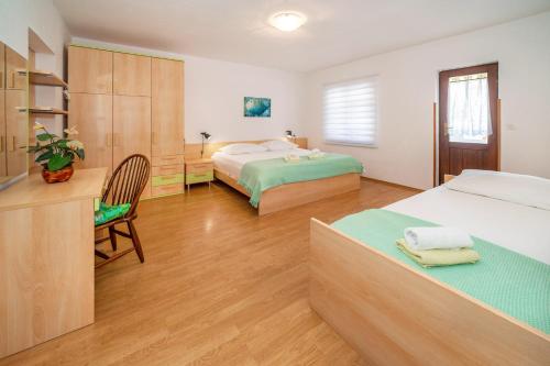 1 dormitorio con 2 camas y escritorio con silla en Apartment & Double Room Stanka, en Baška