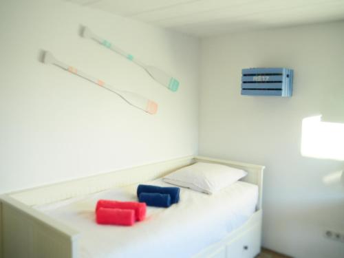 une chambre blanche avec deux oreillers rouges et bleus dans l'établissement Maison de famille Entre bois et sel avec piscine privée chauffée, à Sainte-Marie de Ré