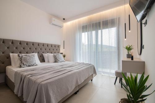 a bedroom with a large bed and a large window at Sun White Villas in Laganas