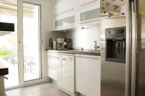 une cuisine avec des armoires blanches, un évier et une fenêtre dans l'établissement Appart 6 Couchages proche centre, grande terrasse, à Nice