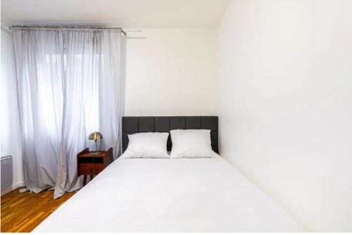 - un lit blanc avec deux oreillers dans une chambre dans l'établissement Jolie 2 pièces à Aubervilliers, à Aubervilliers