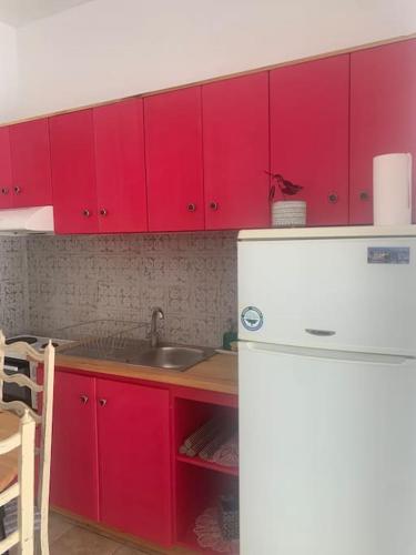 a kitchen with red cabinets and a white refrigerator at Γ2 - The sunlight one in Aígio