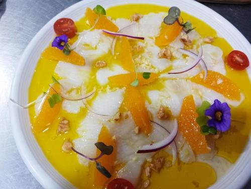 a white plate of food with fruit and vegetables at Restaurante & Hotel Rural El Mirador de Trevejo,ideal para parejas in Villamiel