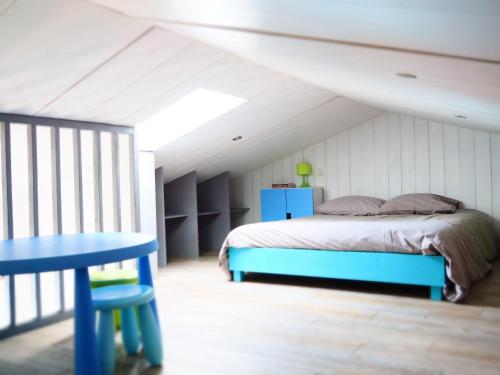 - une chambre avec un lit et une table bleue dans l'établissement Maison de famille Entre bois et sel avec piscine privée chauffée, à Sainte-Marie de Ré