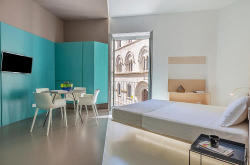 Fiveplace Design Suites & Apartments في تراباني: غرفة نوم بسرير وطاولة مع كراسي