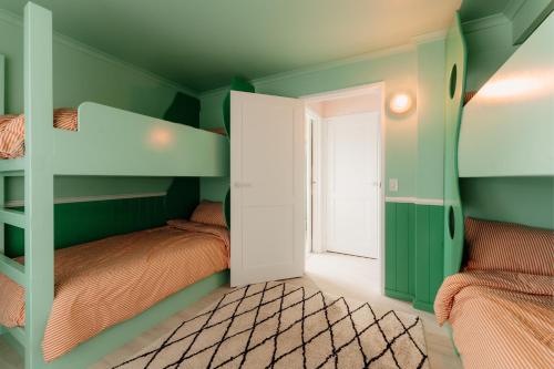 a green room with bunk beds and a window at Sunny Beach Box in Sunderland Bay