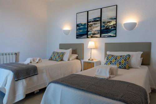 カルヴォエイロにあるApartamentos - Solar Vale Covoのベッド2台 壁にランプ2つが備わる客室です。