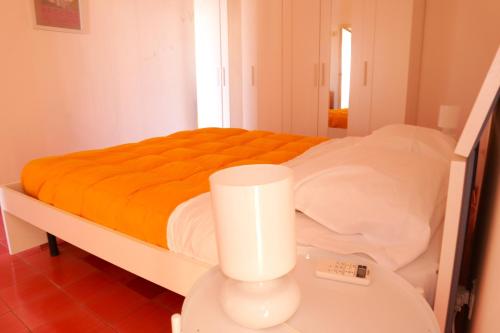 uma cama branca com um cobertor laranja sobre uma mesa em La casa sul porto - Marina Grande port em Procida