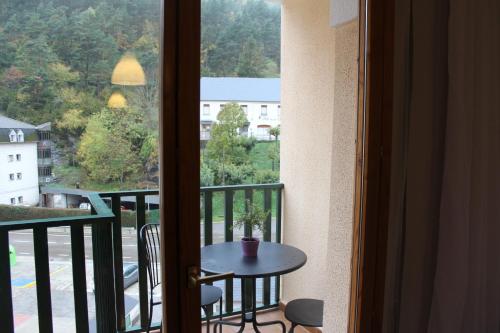 a room with a balcony with a table and a window at Vivienda Turística Pirineos XXI in Canfranc-Estación