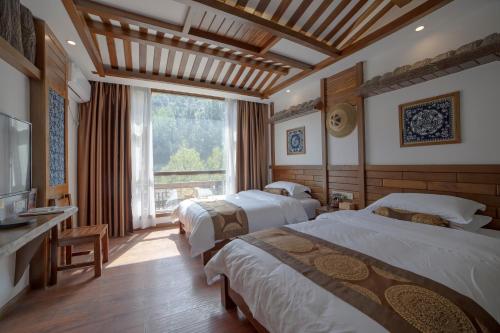 um quarto de hotel com duas camas e uma janela em Zhangjiajie Memory Inn em Zhangjiajie