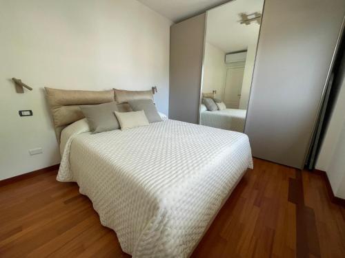 a bedroom with a large white bed and a mirror at La Rosa del Lago in Lenno