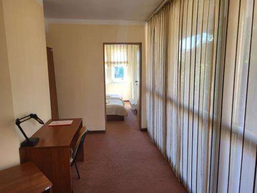 a hotel room with a bedroom and a desk and a bed at Mokyklos viešbutis in Šilutė