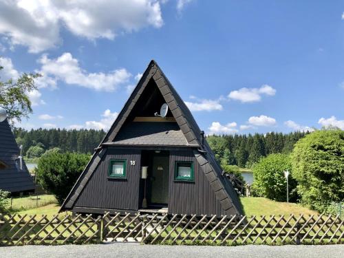 una pequeña casa negra con un techo puntiagudo en Holiday home in Clausthal Zellerfeld with garden furniture, en Clausthal-Zellerfeld