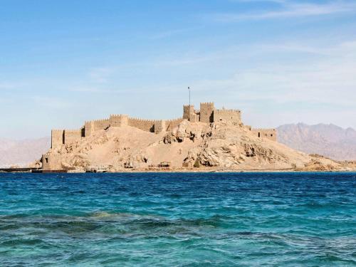 a castle on an island in the middle of the ocean at Movenpick Taba Resort & Spa in Taba