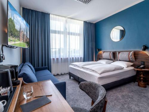 1 dormitorio con cama, mesa y sofá en Mercure Hotel Luebeck City Center en Lübeck