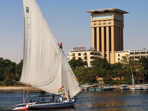 un voilier dans l'eau avec un bâtiment en arrière-plan dans l'établissement Mövenpick Resort Aswan, à Assouan