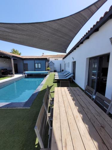 un patio avec une terrasse en bois et une piscine dans l'établissement Maison de famille Entre bois et sel avec piscine privée chauffée, à Sainte-Marie de Ré