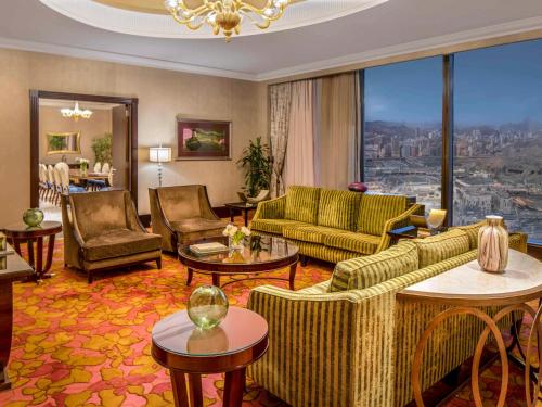 a living room with couches and tables and a large window at Makkah Clock Royal Tower, A Fairmont Hotel in Makkah