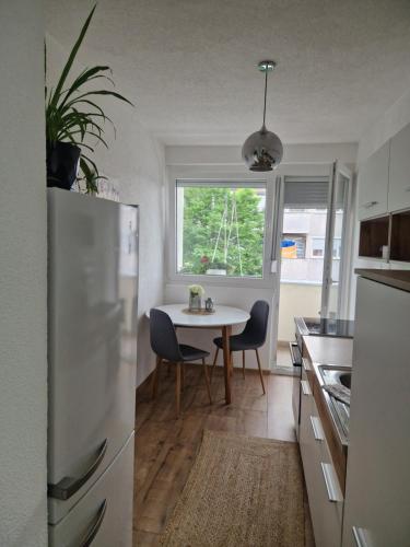 une cuisine avec une table et un réfrigérateur blanc dans l'établissement Blue Apartment, à Bihać