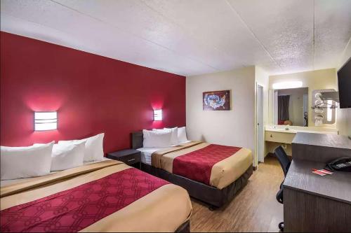 Habitación de hotel con 2 camas y pared roja en Super 8 by Wyndham Charleston WV, en Charleston
