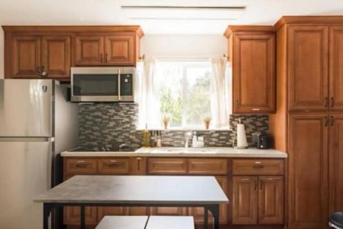 a kitchen with wooden cabinets and a stainless steel refrigerator at Modern Private Unit With Serene Backyard in San Jose