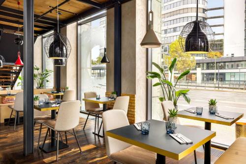 a restaurant with tables and chairs and windows at Vienna House by Wyndham Andel's Berlin in Berlin